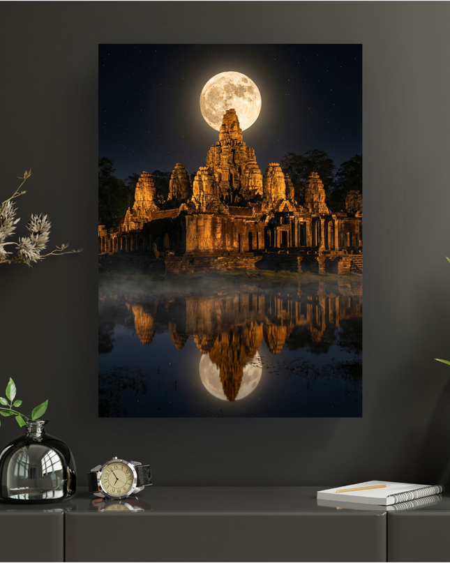 Une affiche verticale représentant le temple de Bayon à Angkor Thom, Cambodge, la nuit. Une pleine lune lumineuse domine les tours du temple, qui sont éclairées par une lumière chaude, créant des reflets dorés sur l'eau brumeuse au premier plan. Le ciel est constellé d'étoiles, et la silhouette des arbres est visible à l'arrière-plan. L'image est sombre et mystérieuse.